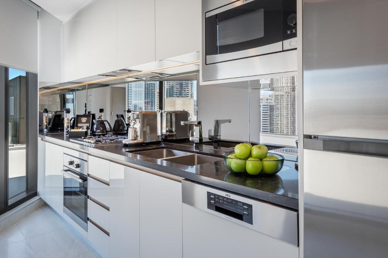 Meriton Suites Sussex Street, Сидни Екстериор снимка The photo shows a modern kitchen featuring sleek cabinetry and stainless steel appliances. There is a glossy countertop with a bowl of green apples as a decoration. The kitchen includes a built-in oven, a microwave, and other kitchen gadgets, along w