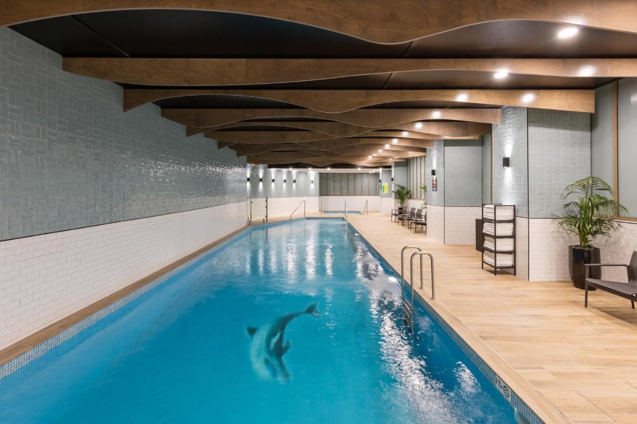 Meriton Suites Sussex Street, Сидни Екстериор снимка The photo shows an indoor swimming pool. The pool features clear blue water, and there is a dolphin swimming in it. The surrounding area has a modern design with curved wooden beams on the ceiling, and the walls are tiled in light colors. There are a