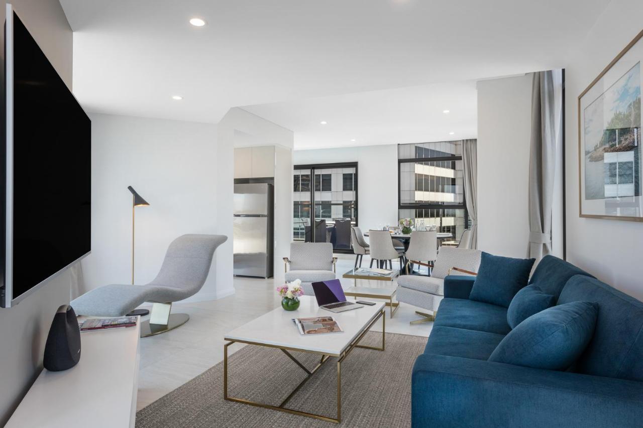 Meriton Suites Sussex Street, Сидни Екстериор снимка The photo shows a modern living space that features a bright and stylish interior. Key elements include:

- A sleek blue sofa and a light gray lounge chair, providing comfortable seating.
- A coffee table with a minimalist design, positioned in front