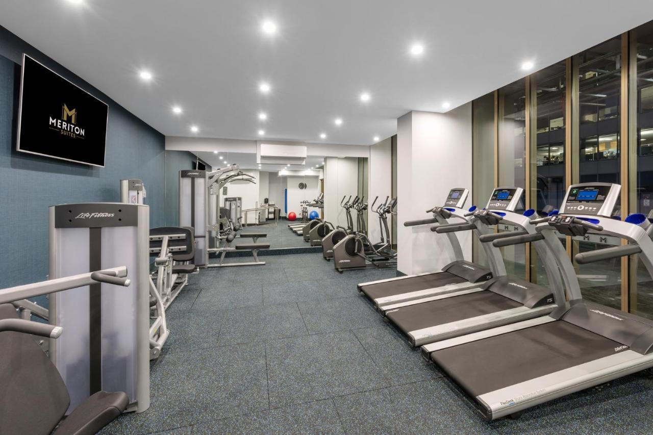 Meriton Suites Sussex Street, Сидни Екстериор снимка The photo shows a modern gym space. It features various exercise equipment, including several treadmills and elliptical machines positioned along one side. On the other side, there are weight machines and additional fitness equipment. The gym has a c